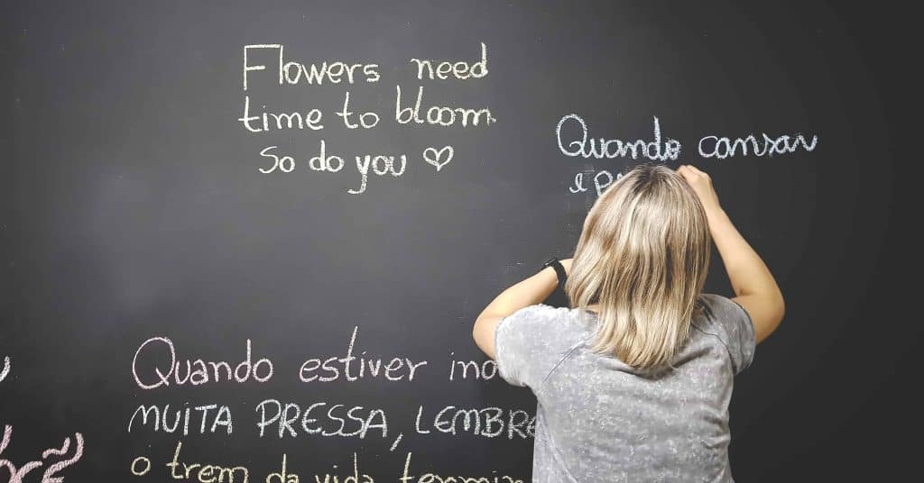 Photo of a young student writing on the blackboard during a foreign language class